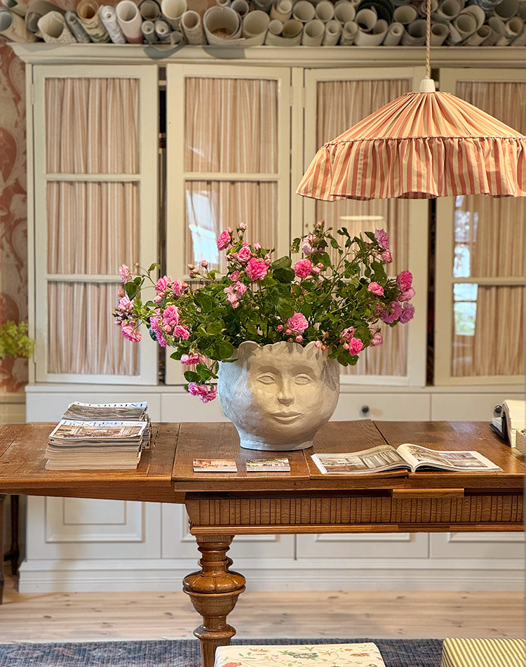 Ett bord med blommor med tyglampan Charlotte i profil