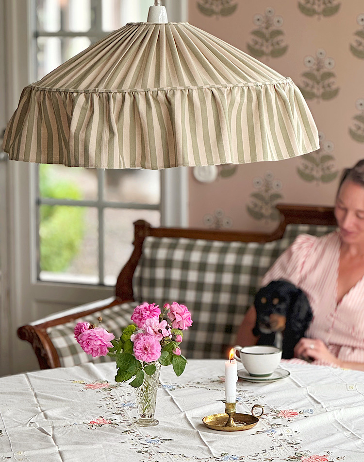 Lina Isaksson sitter i köket och i taket hänger tyglampan Charlotte